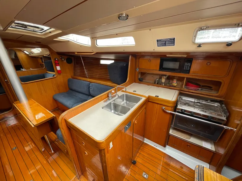 Slide: The Image of Interior of 1991 Beneteau Oceanis 390 yacht with kitchen, seating, and wooden finishes. - 4