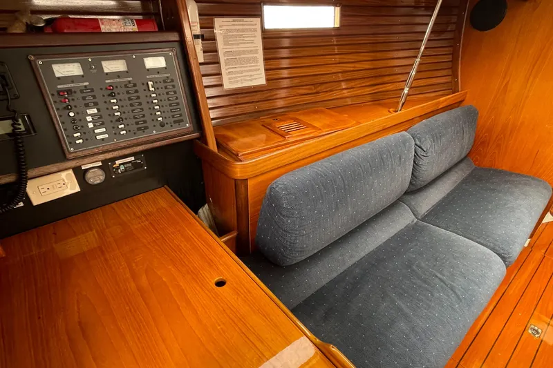 Slide: The Image of Interior of 1991 Beneteau Oceanis 390 sailboat with blue cushioned seating and control panel. - 7