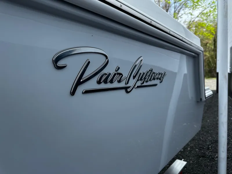 Slide: The Image of Close-up of Pair Customs 27 boat logo, 2025 model, on sleek white surface. - 7