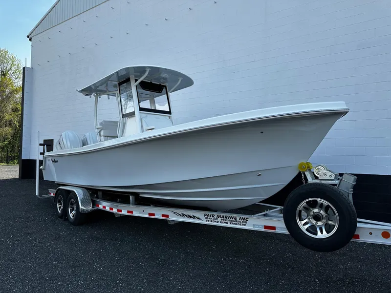 Slide: The Image of 2025 Pair Customs 27 boat on trailer, parked outdoors near a white building. - 3