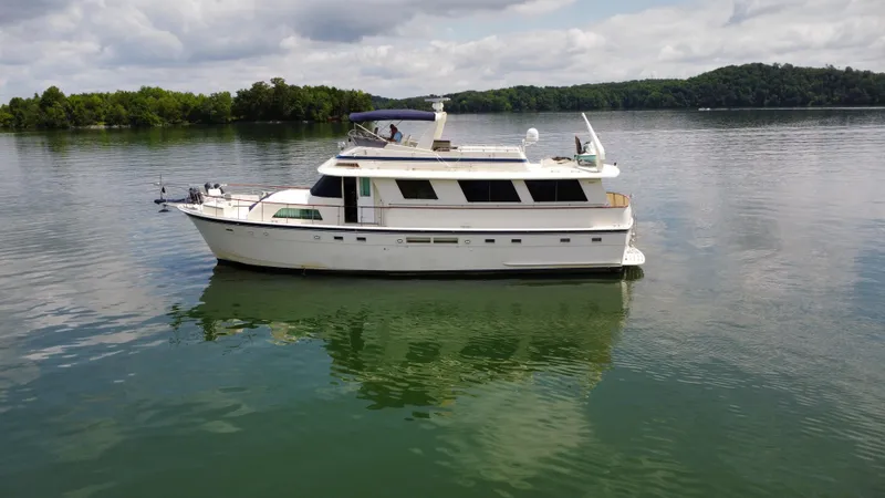 Slide: The Image of 1987 Hatteras 63 Motor Yacht on calm lake with lush green shoreline. - 11