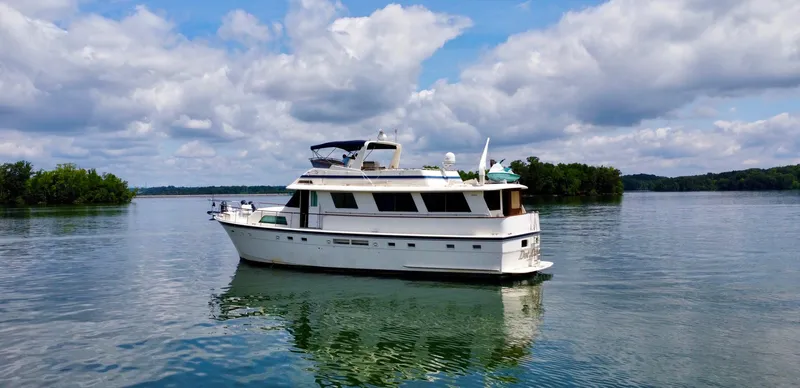 Slide: The Image of 1987 Hatteras 63 Motor Yacht on serene lake under cloudy sky. - 12
