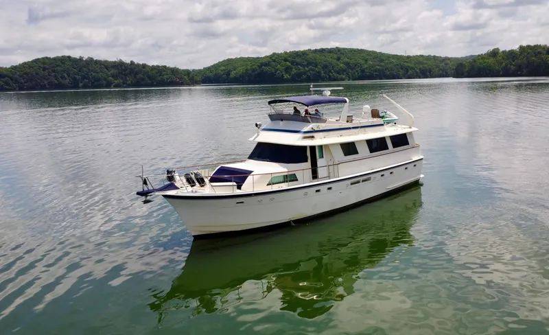 Slide: The Image of 1987 Hatteras 63 Motor Yacht on serene lake with lush green hills. - 13