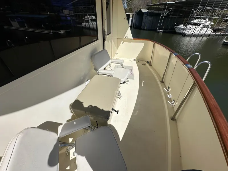 Slide: The Image of 1987 Hatteras 63 Motor Yacht deck with seating, docked near water. - 21