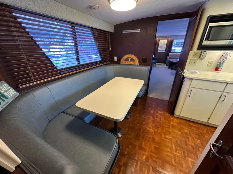 Slide: The Image of 1987 Hatteras 63 Motor Yacht interior with dining area, wood flooring, and cozy seating. - 22