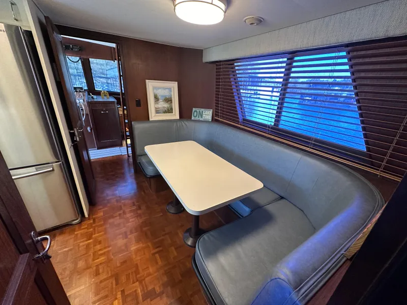 Slide: The Image of 1987 Hatteras 63 Motor Yacht interior with dining area, curved seating, and wood flooring. - 24