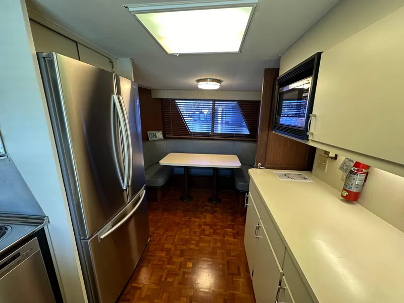 Slide: The Image of 1987 Hatteras 63 Motor Yacht kitchen with stainless steel fridge, dining nook, and wood flooring. - 28
