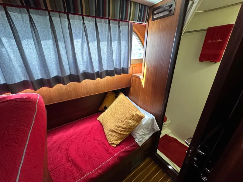 Slide: The Image of Cozy cabin interior of 1987 Hatteras 63 Motor Yacht with red bedding and wooden accents. - 41
