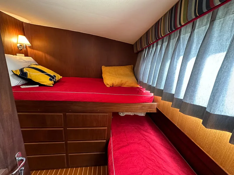 Slide: The Image of Cozy cabin interior of 1987 Hatteras 63 Motor Yacht with red bedding and wood paneling. - 43
