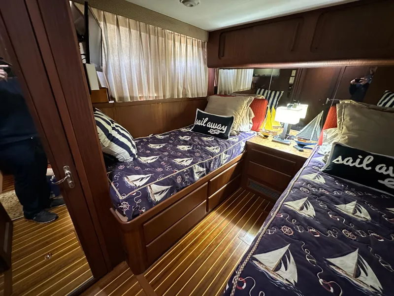 Slide: The Image of 1987 Hatteras 63 Motor Yacht cabin with twin beds, nautical decor, and wooden flooring. - 47