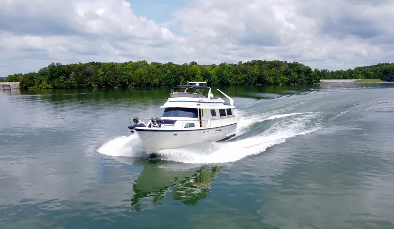 Slide: The Image of 1987 Hatteras 63 Motor Yacht cruising on a serene lake under a cloudy sky. - 5