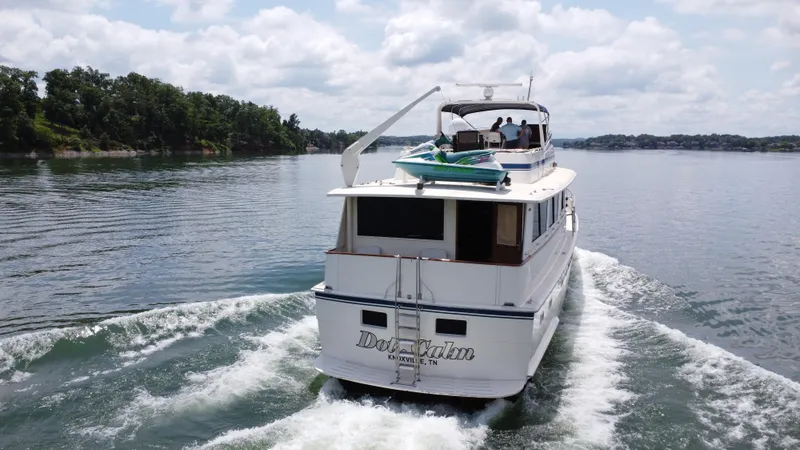 Slide: The Image of 1987 Hatteras 63 Motor Yacht cruising on a serene lake under a cloudy sky. - 7