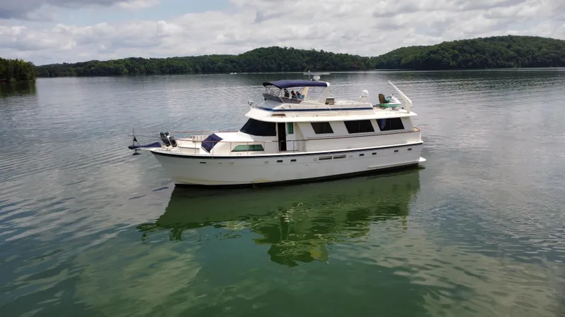 Slide: The Image of 1987 Hatteras 63 Motor Yacht on a serene lake with lush green hills. - 9