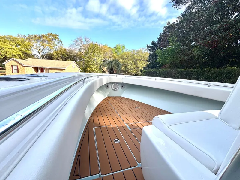Slide: The Image of 2015 Contender 30 ST boat with teak deck and white seating, surrounded by trees. - 14