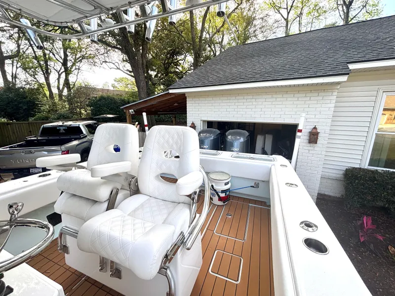 Slide: The Image of 2015 Contender 30 ST boat with white seating and teak deck, parked near a garage. - 22