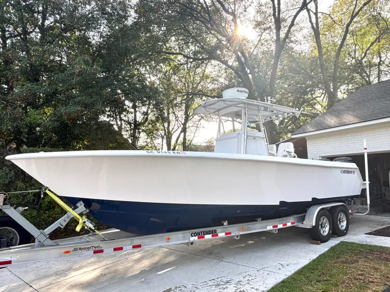 Slide: The Image of 2015 Contender 30 ST boat on trailer, parked in driveway, surrounded by trees. - 3