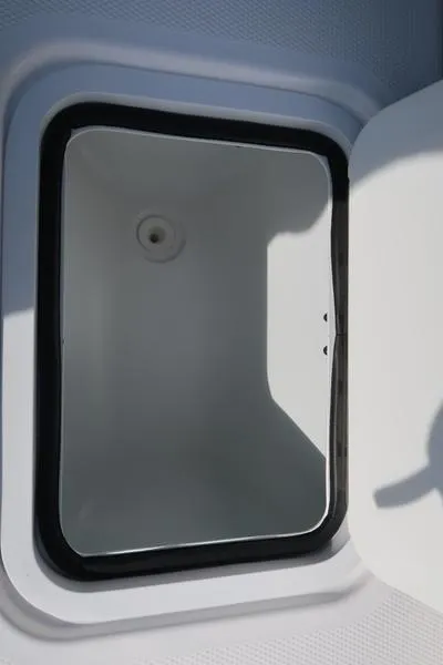 Slide: The Image of 2023 Hurricane SunDeck Sport 205 IO storage compartment, open lid, white interior. - 26