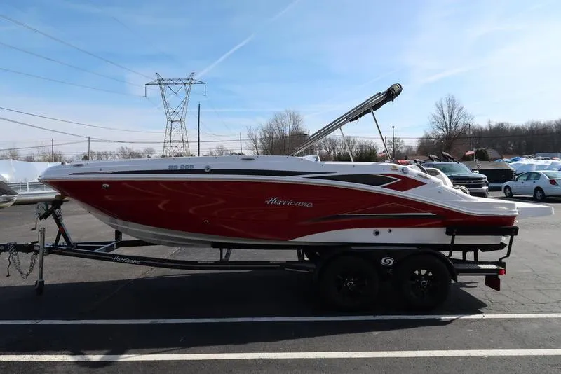 Slide: The Image of 2023 Hurricane SunDeck Sport 205 IO boat on trailer, red and white design, parked outdoors. - 6