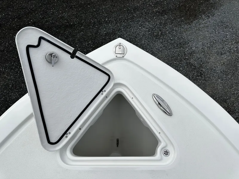 Slide: The Image of Open storage compartment on 2025 Pair Customs 24OS boat, featuring a triangular hatch design. - 19