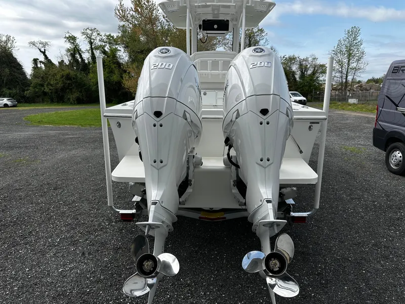 Slide: The Image of Twin outboard motors on a 2025 Pair Customs 24OS boat, parked on gravel. - 2