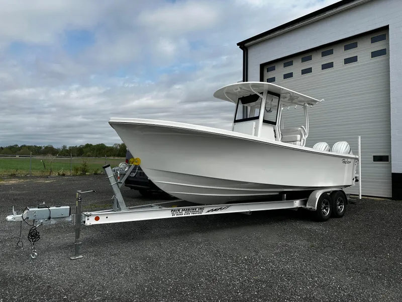 Slide: The Image of 2025 Pair Customs 24OS boat on trailer, parked outside a garage. - 5