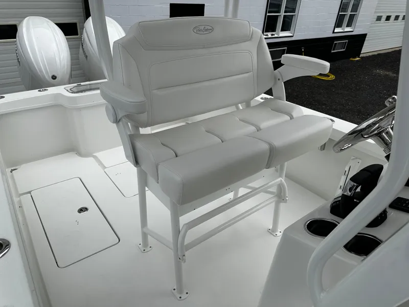 Slide: The Image of White seating area on 2025 Pair Customs 24OS boat, featuring cushioned bench and steering console. - 7