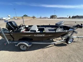 Slide: The Image of 2014 Lowe FM 160 T fishing boat on trailer in open parking lot. - 0