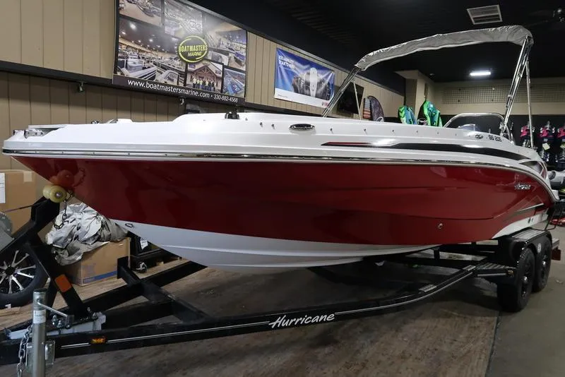 Slide: The Image of 2023 Hurricane SunDeck Sport 205 OB boat with red hull on display indoors. - 7