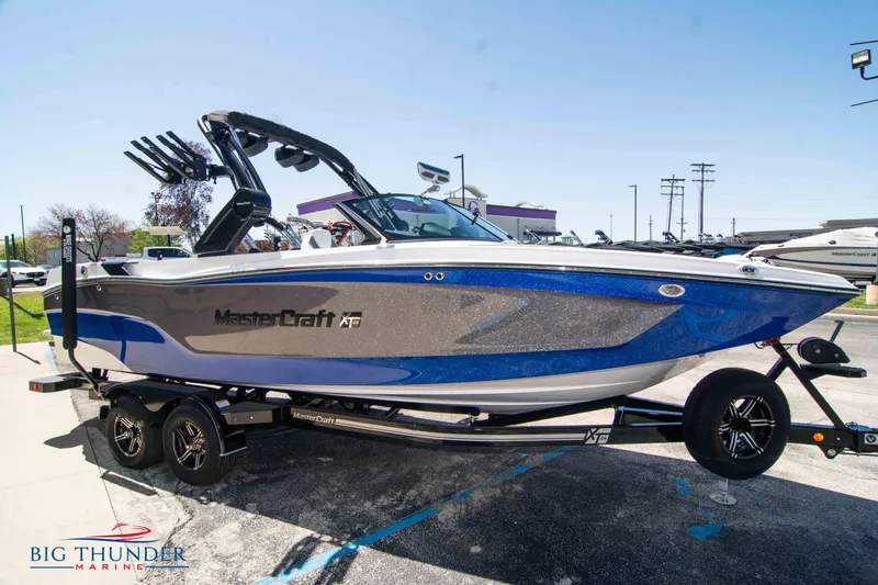 Slide: The Image of 2024 MasterCraft XT24 boat in blue and gray on a trailer at Big Thunder Marine. - 3