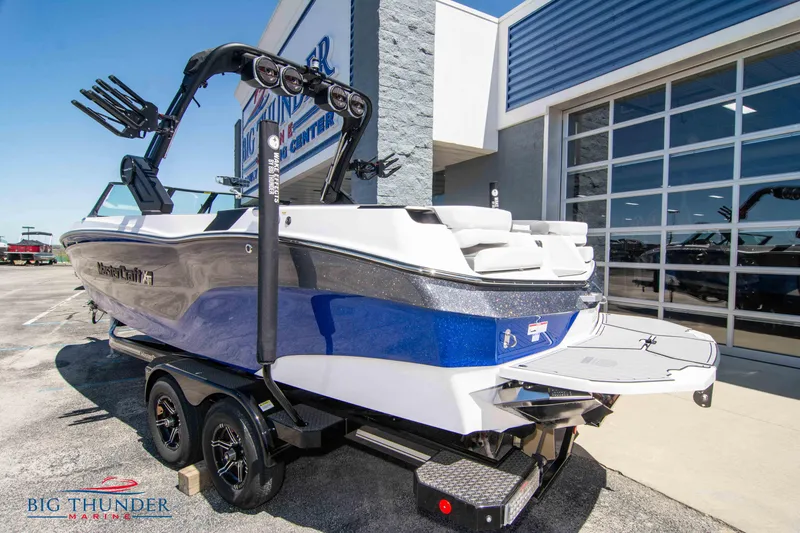 Slide: The Image of 2024 MasterCraft XT24 boat in blue and white, parked outside a dealership. - 4