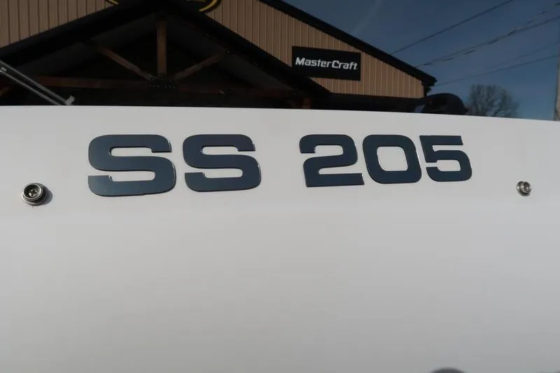 Slide: The Image of 2023 Hurricane SunDeck Sport 205 OB boat with "SS 205" lettering, MasterCraft sign in background. - 13
