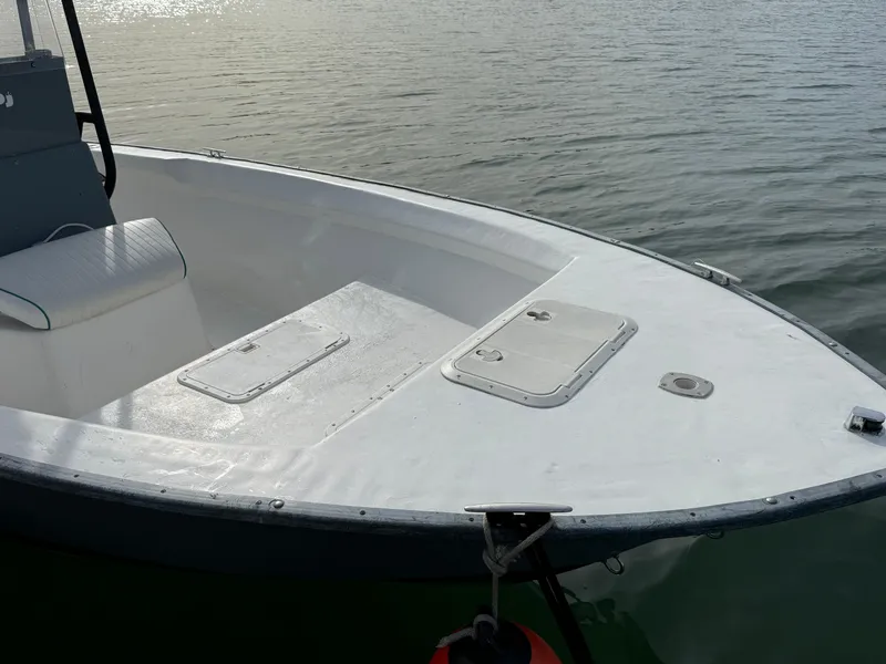 Slide: The Image of 2003 Key Largo 216cc boat on calm water, featuring a spacious deck and storage compartments. - 11