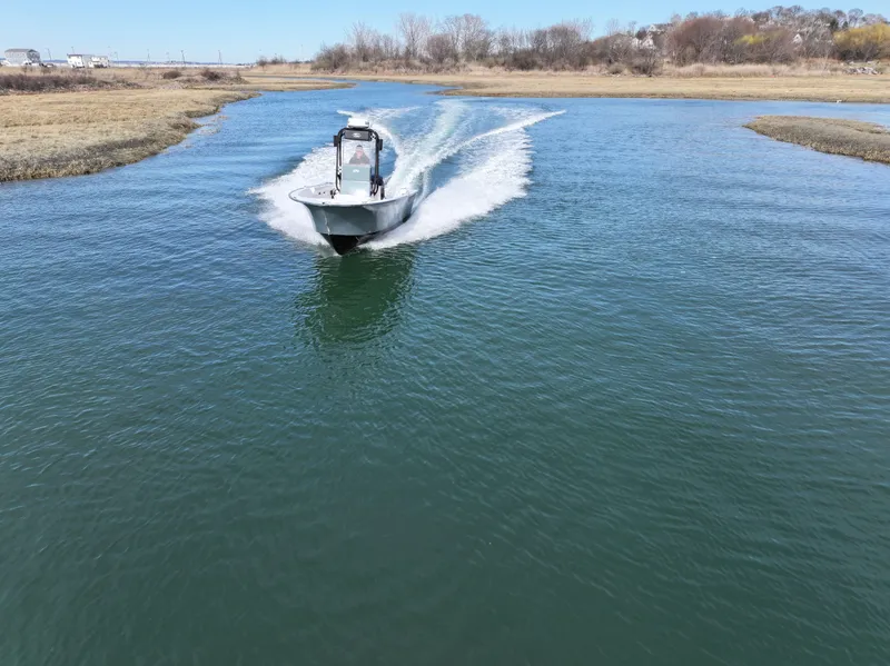 Slide: The Image of 2003 Key Largo 216cc boat cruising on a narrow waterway, surrounded by grassy banks. - 9