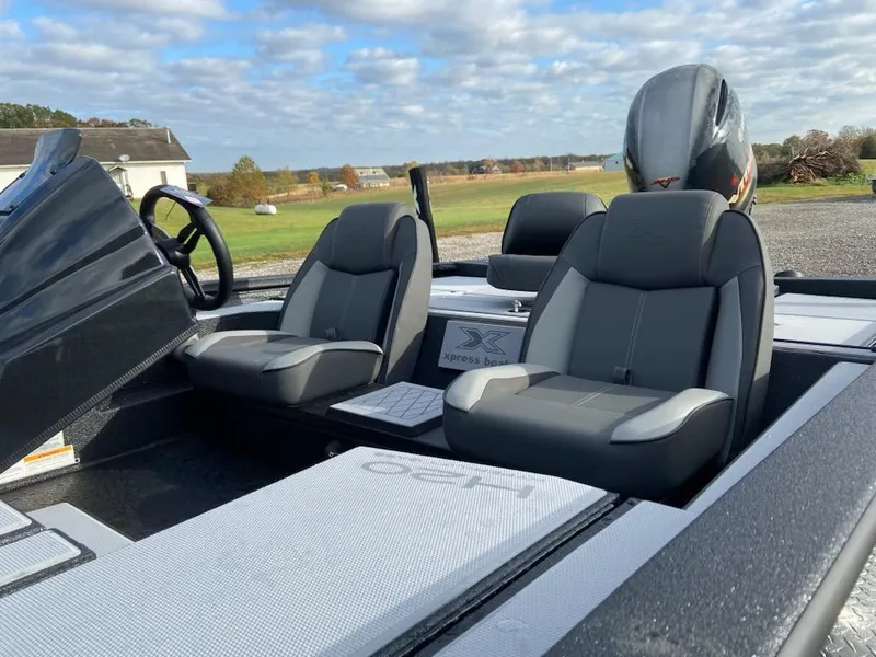 Slide: The Image of 2025 Xpress H20 Bass boat interior with dual seats and steering wheel, set outdoors. - 4
