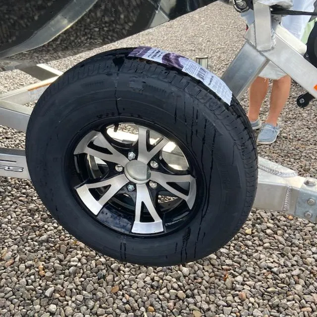 Slide: The Image of Trailer wheel of 2025 Xpress H20 Bass boat on gravel surface. - 8