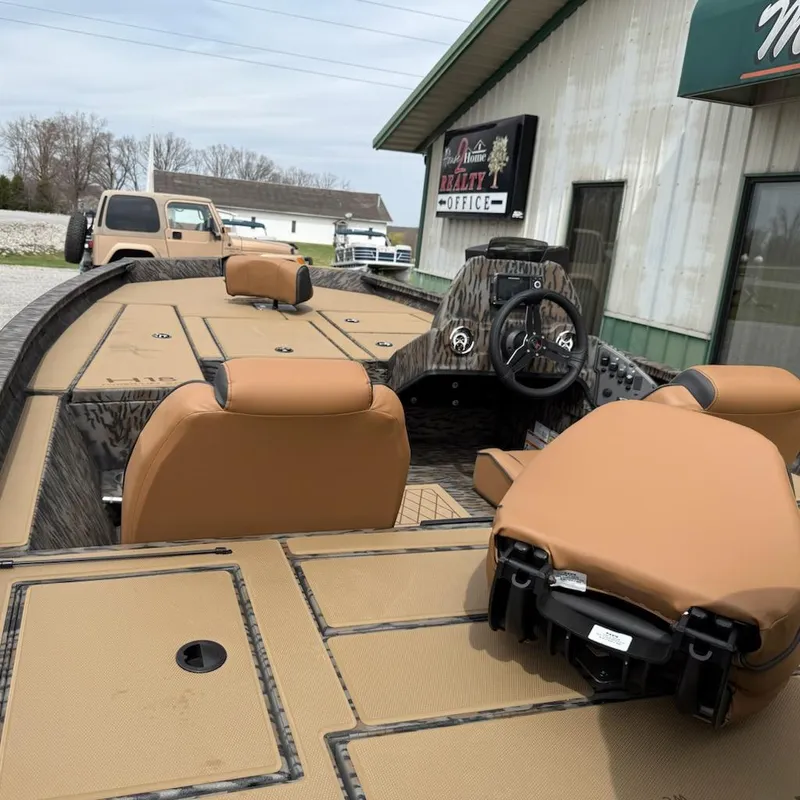 Slide: The Image of 2025 Xpress H18 Bass boat with tan seats and modern dashboard, parked outside a building. - 4