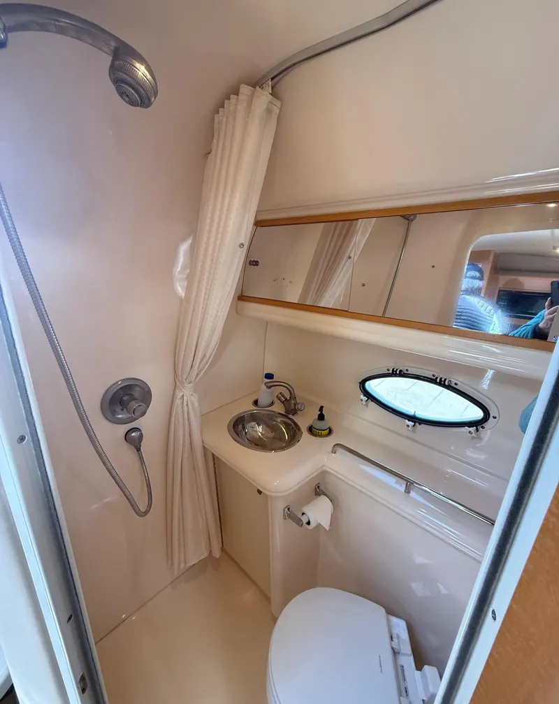 Slide: The Image of 2008 Larson 310 Cabrio bathroom with shower, sink, and porthole window. - 16
