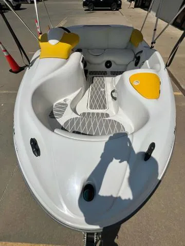 Slide: The Image of 2004 Sea-Doo Sportster LE DI boat with white and yellow seating, docked on pavement. - 4