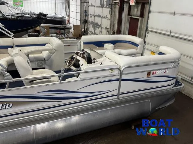 Slide: The Image of 2002 Godfrey 220 DF Pontoon boat in a garage, featuring white and blue seating. - 14