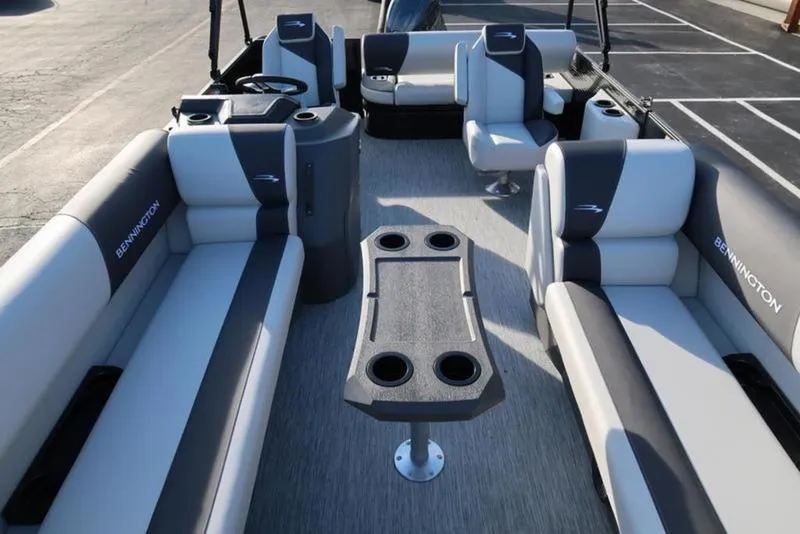 Slide: The Image of 2025 Bennington 22 SSB pontoon boat interior with seating and table, docked in a parking lot. - 10