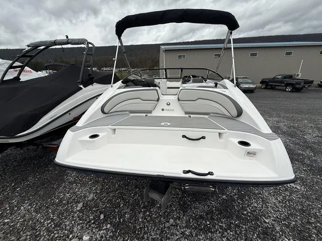 Slide: The Image of 2020 Yamaha Boats SX190 with sleek design, rear view, and bimini top in a parking lot. - 13