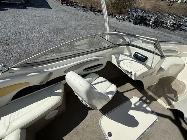 Slide: The Image of 2006 Stingray 195LR boat interior with white seating and dashboard, parked on gravel. - 6
