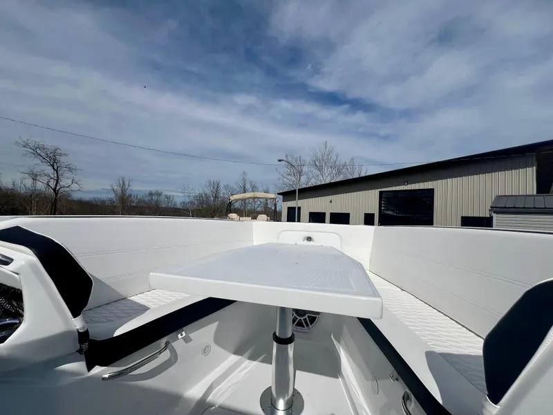 Slide: The Image of 2025 Nor-Tech 390 Sport Center Console boat interior with seating and table under a cloudy sky. - 42