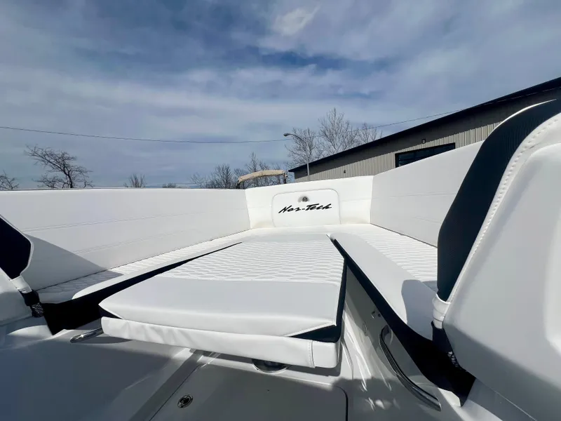 Slide: The Image of 2025 Nor-Tech 390 Sport Center Console boat interior with white seating under a cloudy sky. - 43