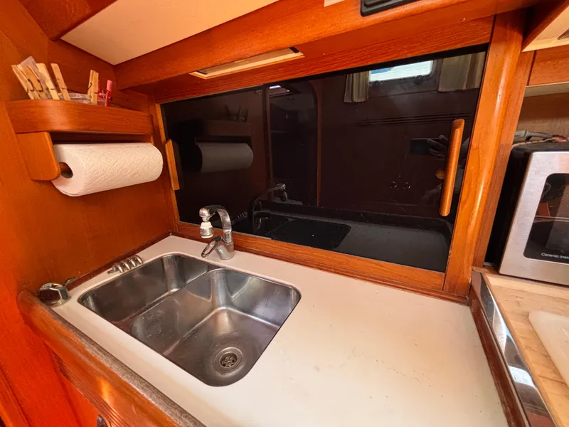 Slide: The Image of Galley sink area in 1994 Nautor Swan 46 MK II yacht, featuring wooden cabinetry and stainless steel sink. - 34
