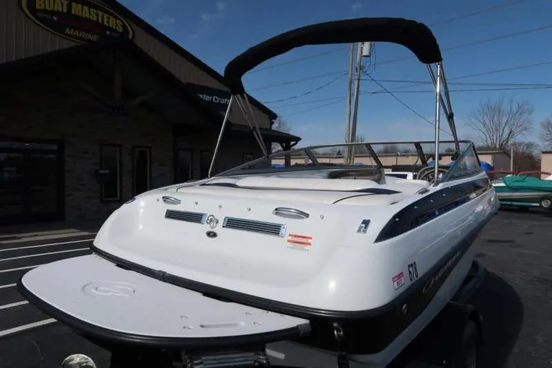 Slide: The Image of 2011 Crownline 18 SS boat with canopy, parked outside a marine dealership. - 6