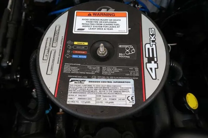 Slide: The Image of Engine cover of a 2011 Crownline 18 SS boat, featuring warning labels and specifications. - 8