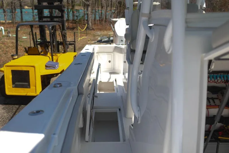 Slide: The Image of 2023 Front Runner 33 Center Console boat interior with storage compartments, parked near a yellow forklift. - 30