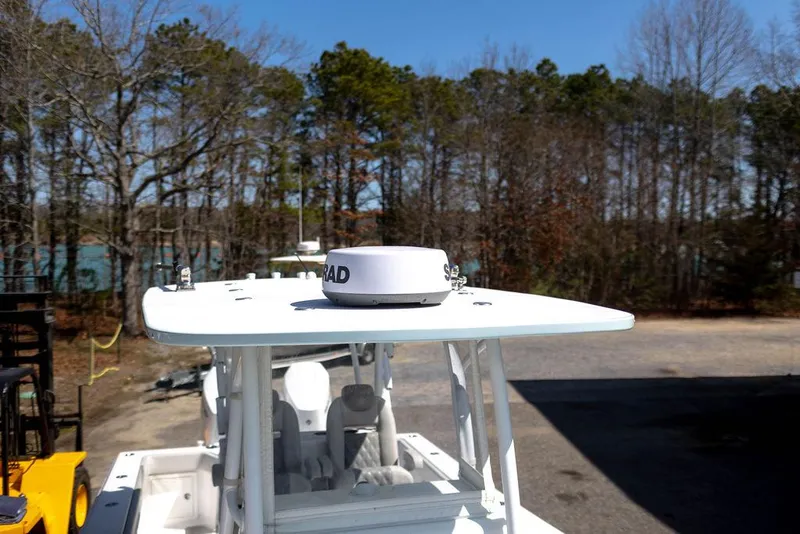 Slide: The Image of 2023 Front Runner 33 Center Console boat with radar, parked outdoors near trees. - 36