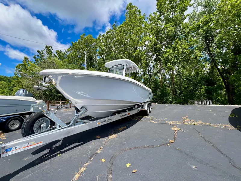 Slide: The Image of 2024 Everglades 285 Center Console boat on trailer, surrounded by trees and blue sky. - 3